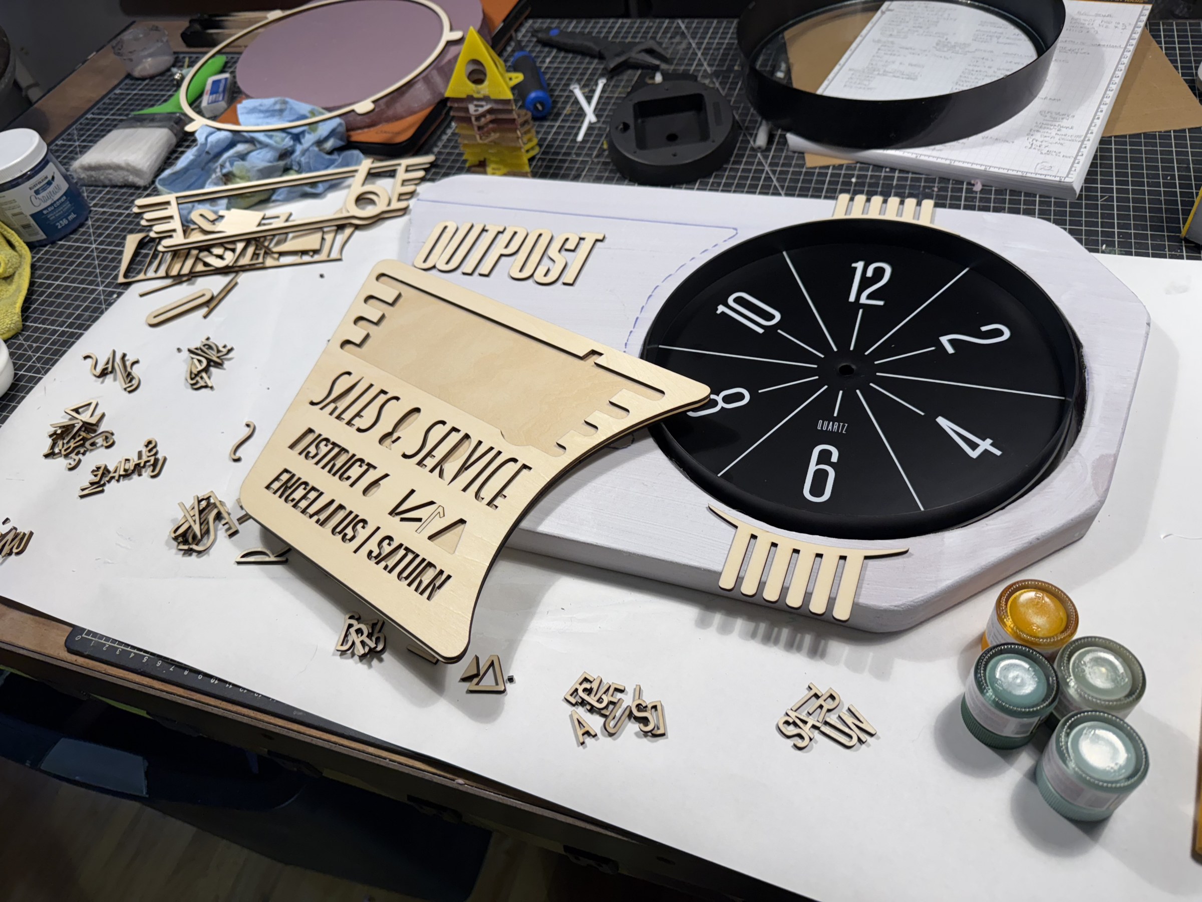 Cut lettering and clock components laid out for assembly